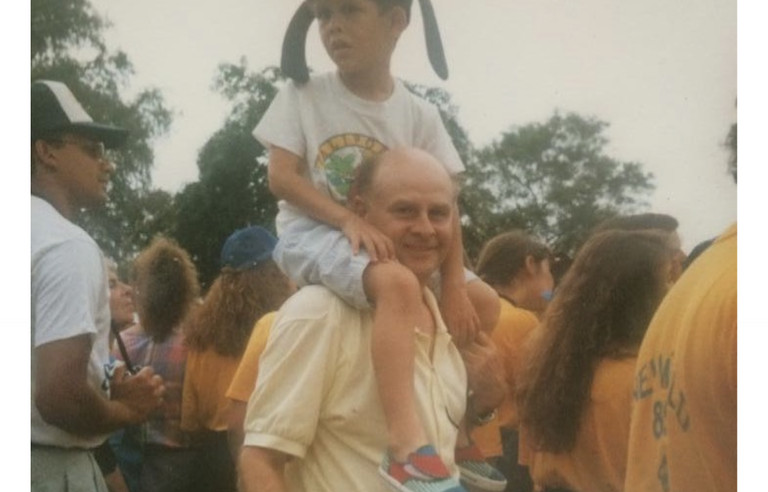 A boy sat on a man's shoulders surrounded by a crows