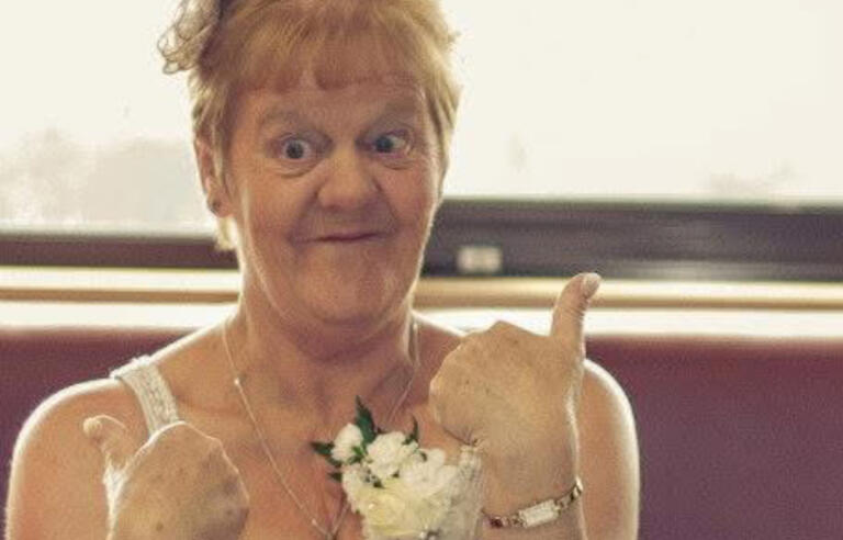 A woman with short blonde hair smiling with her thumbs up