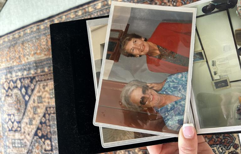 A photo of a woman with a blonde updo, sunglasses and blue patterned top and a woman with short brown hair and red jacket