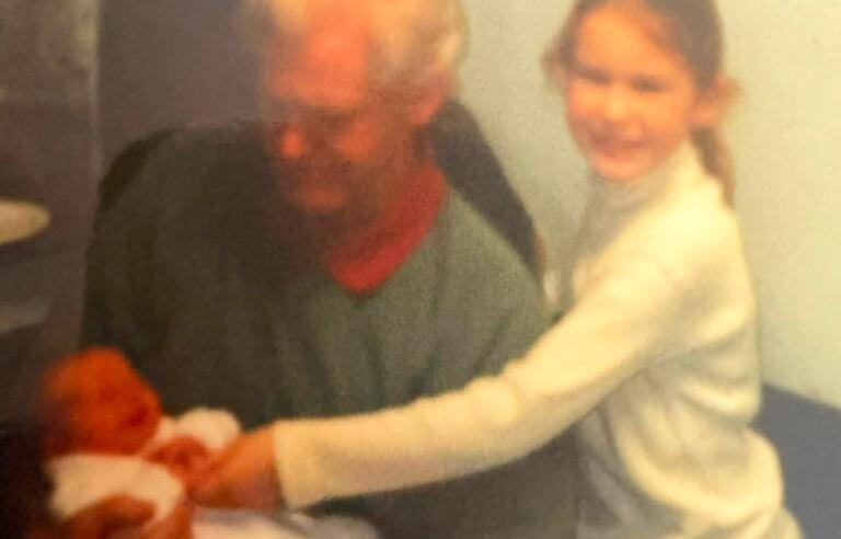 A man holding a baby and a girl holding the baby's hand