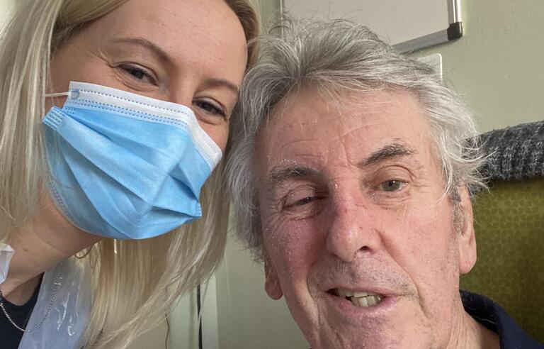 A woman with blonde hair and wearing a blue mask with an older man with grey hair and a blue stripy t shirt