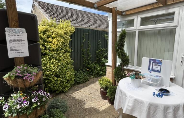 A table with a sign on the patio of a garden