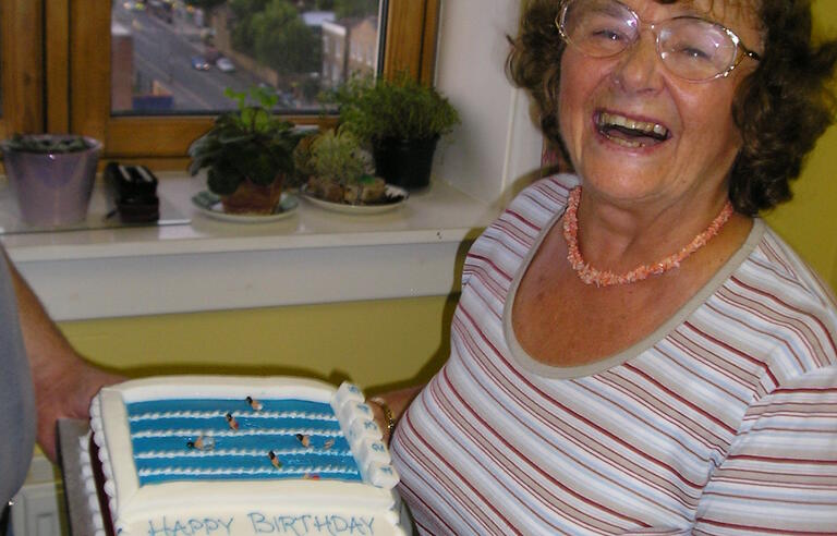 A woman in a stripy top smiling while holding a cake
