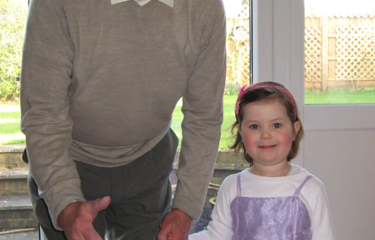 A man leaning towards a camera holding a young girl's hand