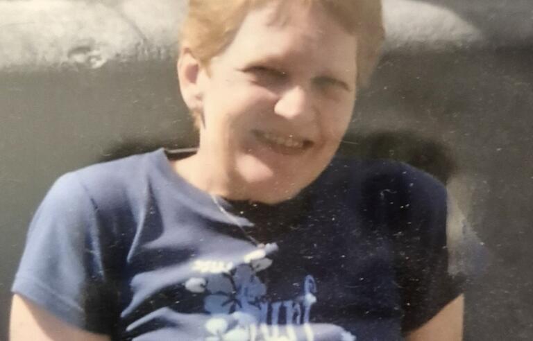 A woman with short blonde hair wearing a patterned blue t-shirt