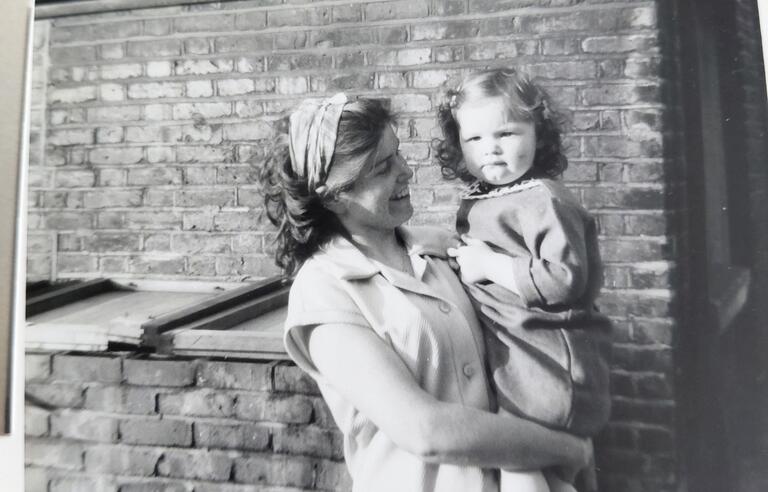 A black and white photo of a woman holding a child in front of a building